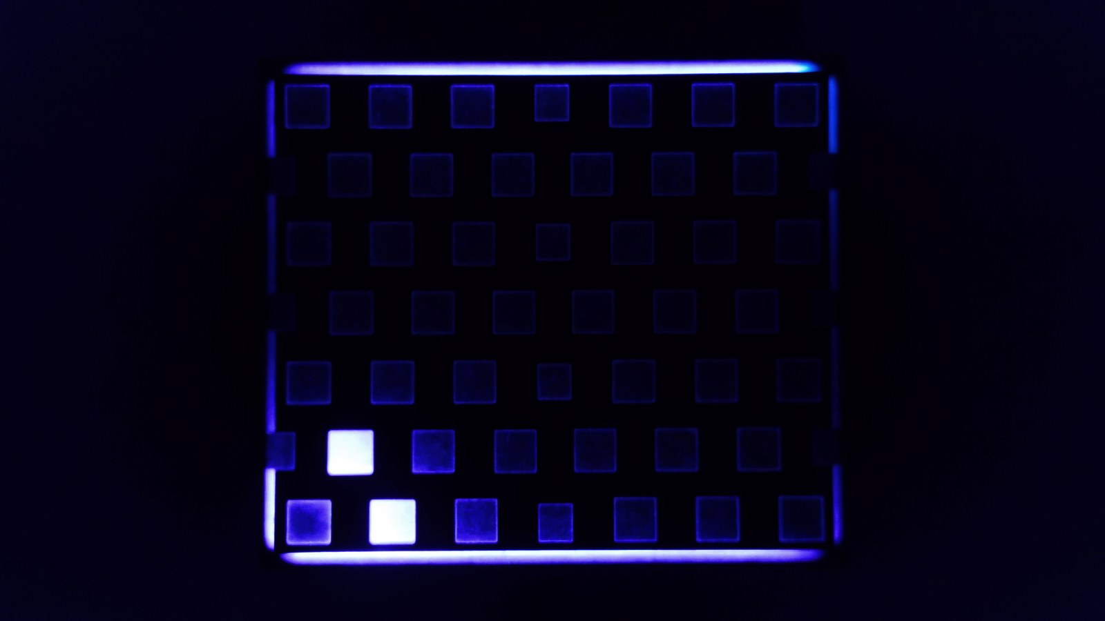 A grid of antenna patches edge-lit in blue, two of them lit bright