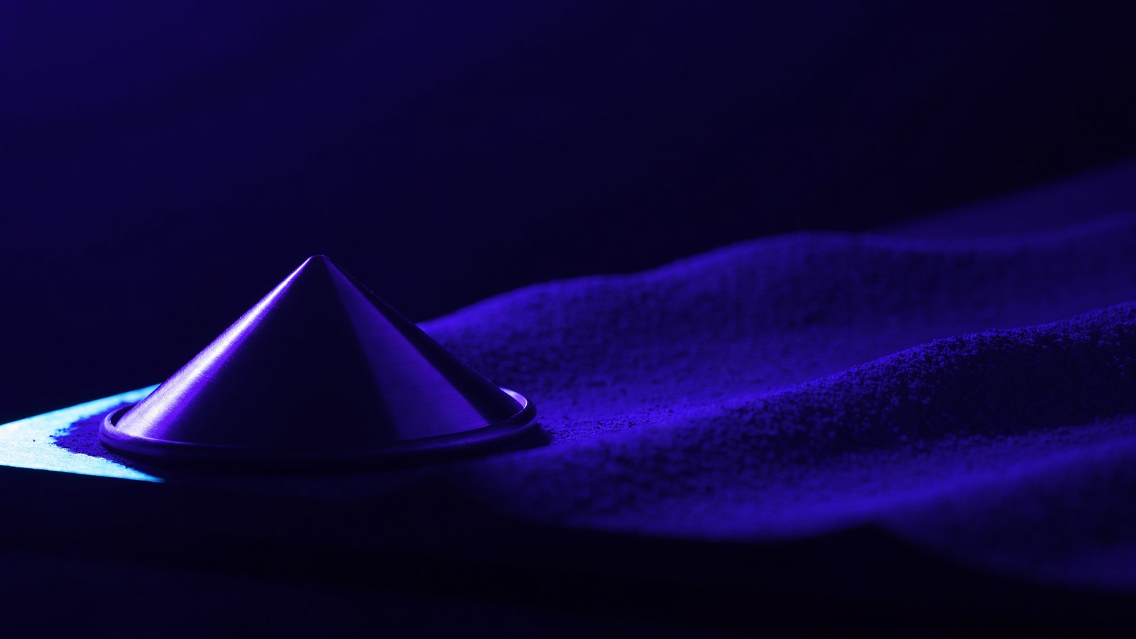 A conical radar reflector on a drift of fine dust under violet light